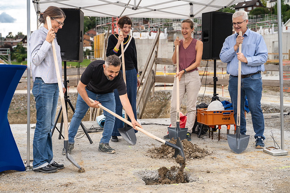 Impression von der Grundsteinlegung: Fünf Personen stehen mit Schaufeln um ein Loch.